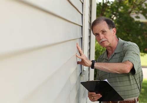 a man inspects vinyl siding paint before removing.