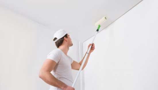 A painter painting ceiling using a roller