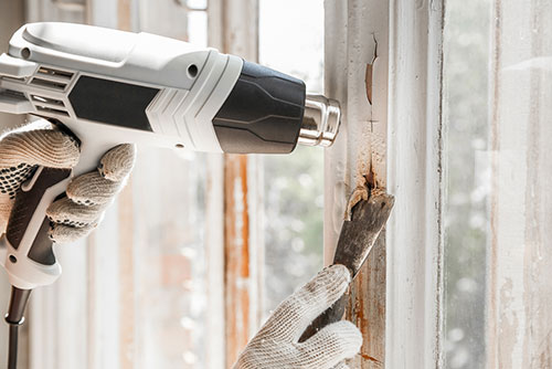 a man removing paint with heat gun