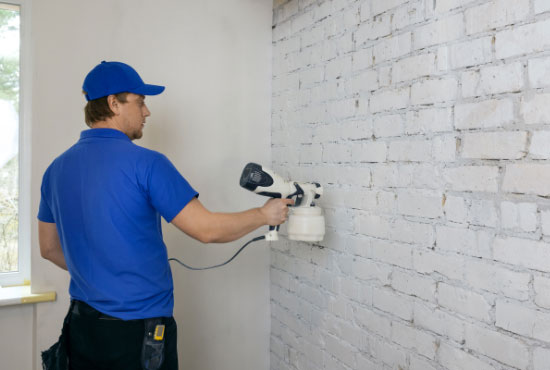 Man painting old interior brick wall